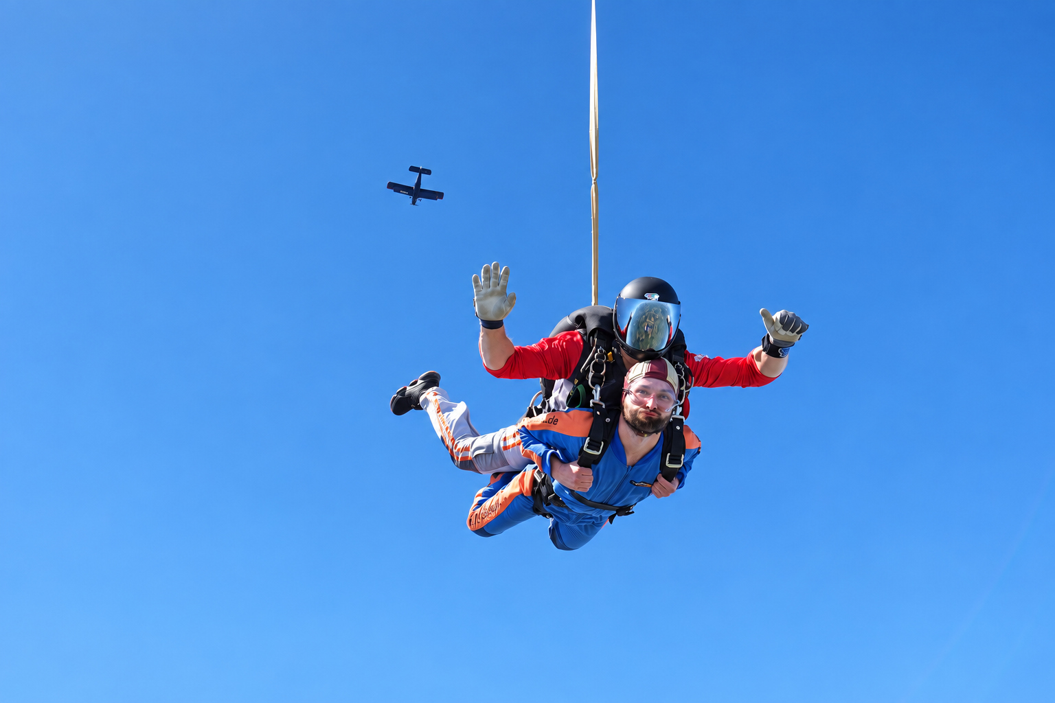 Tandemgast und Tandemmaster im freien Fall mit dem Flugzeug im blauen Himmel
